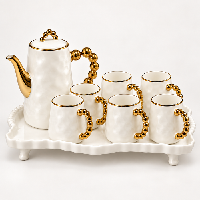 Weiße Kaffeetasse mit goldfarbenem Perlenhenkel und passender Kanne