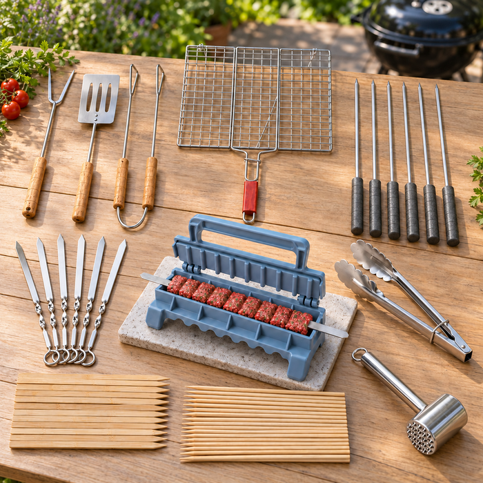 Grillzubehör-Set auf einem Gartentisch mit geöffneter Kebabpresse und Hackfleisch am Spieß, Grillbesteck, Grillkorb und verschiedenen Spießen.