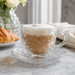 Klare Teetasse aus Glas mit Henkel und dekorativer Untertasse